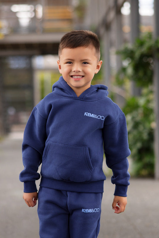 Child wearing the Remy & Co. Navy Blue Puff Print Hoodie Tracksuit Set outdoors as a close up shot.