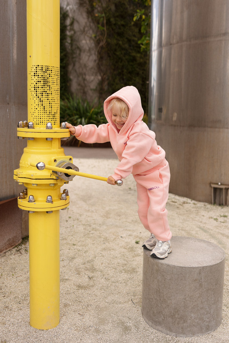 Child wearing the Remy & Co. Pink Puff Print Hoodie Tracksuit Set playing outdoors.