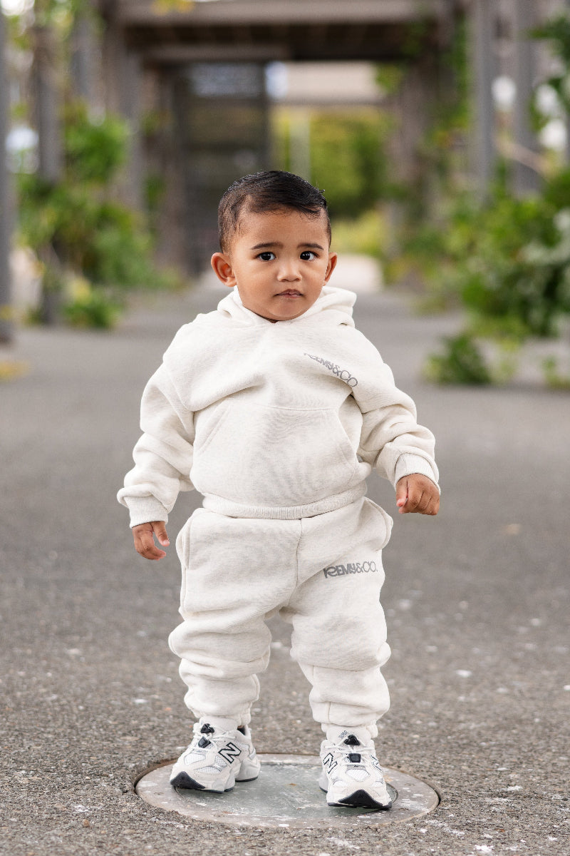 Child wearing Remy & Co. Light Grey Puff Print Hoodie Tracksuit Set outdoors.