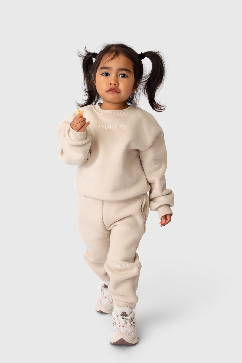 Child wearing the Remy & Co. Beige crewneck sweatshirt and matching joggers on a white background.