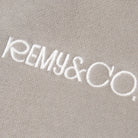 Close-up of the Remy & Co. embroidered logo on Dark Grey coloured fabric.