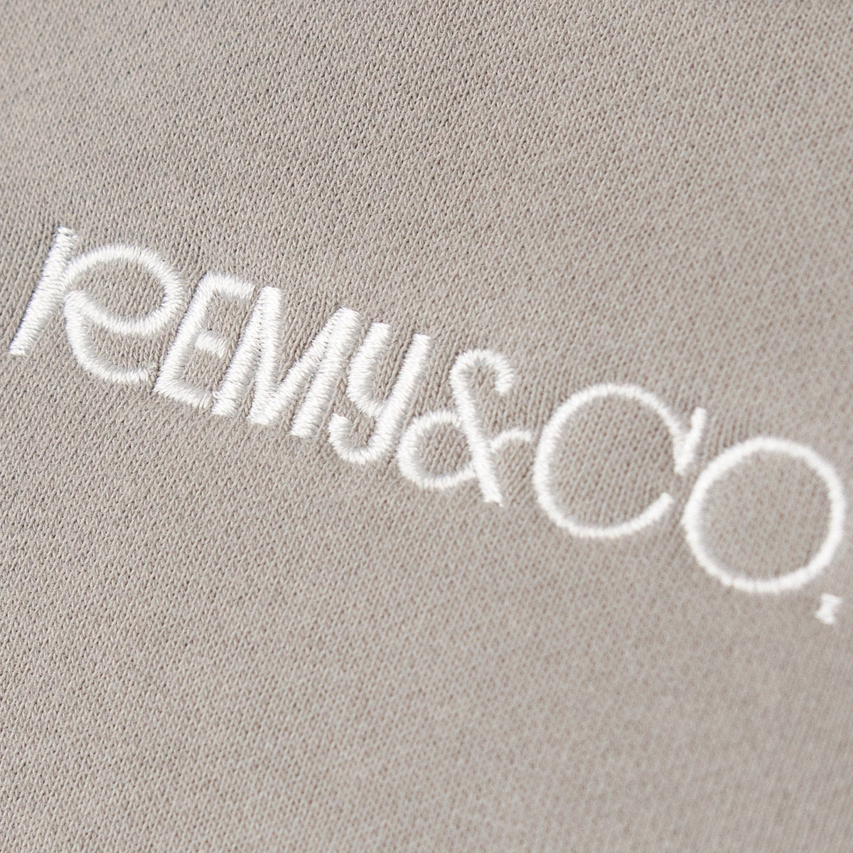 Close-up of the Remy & Co. embroidered logo on Dark Grey coloured fabric.