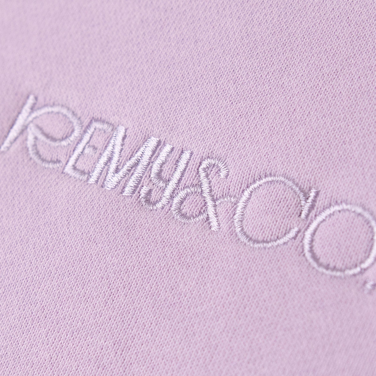 Close-up of the tonal embroidered Remy & Co. logo on Lilac fabric