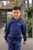 Child wearing the Remy & Co. Navy Blue Puff Print Hoodie Tracksuit Set outdoors as a close up shot.