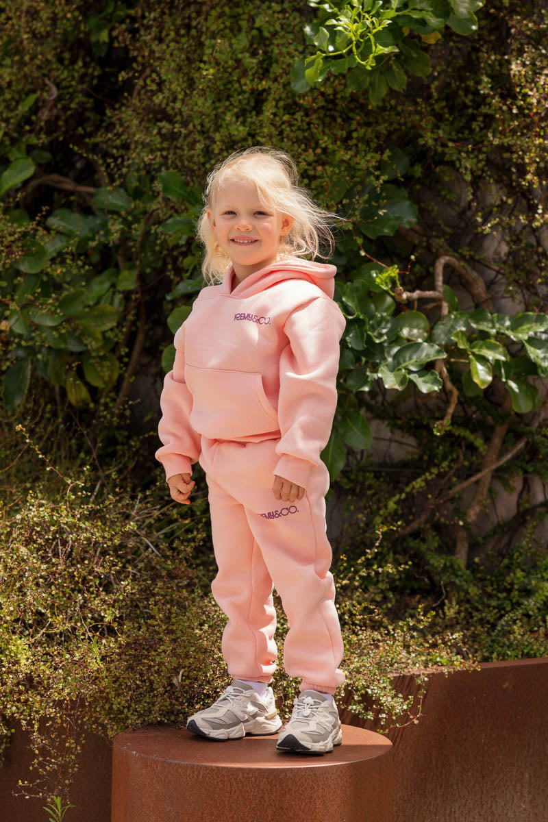 Child wearing the Remy & Co. Pink Puff Print Hoodie Tracksuit Set outdoors.